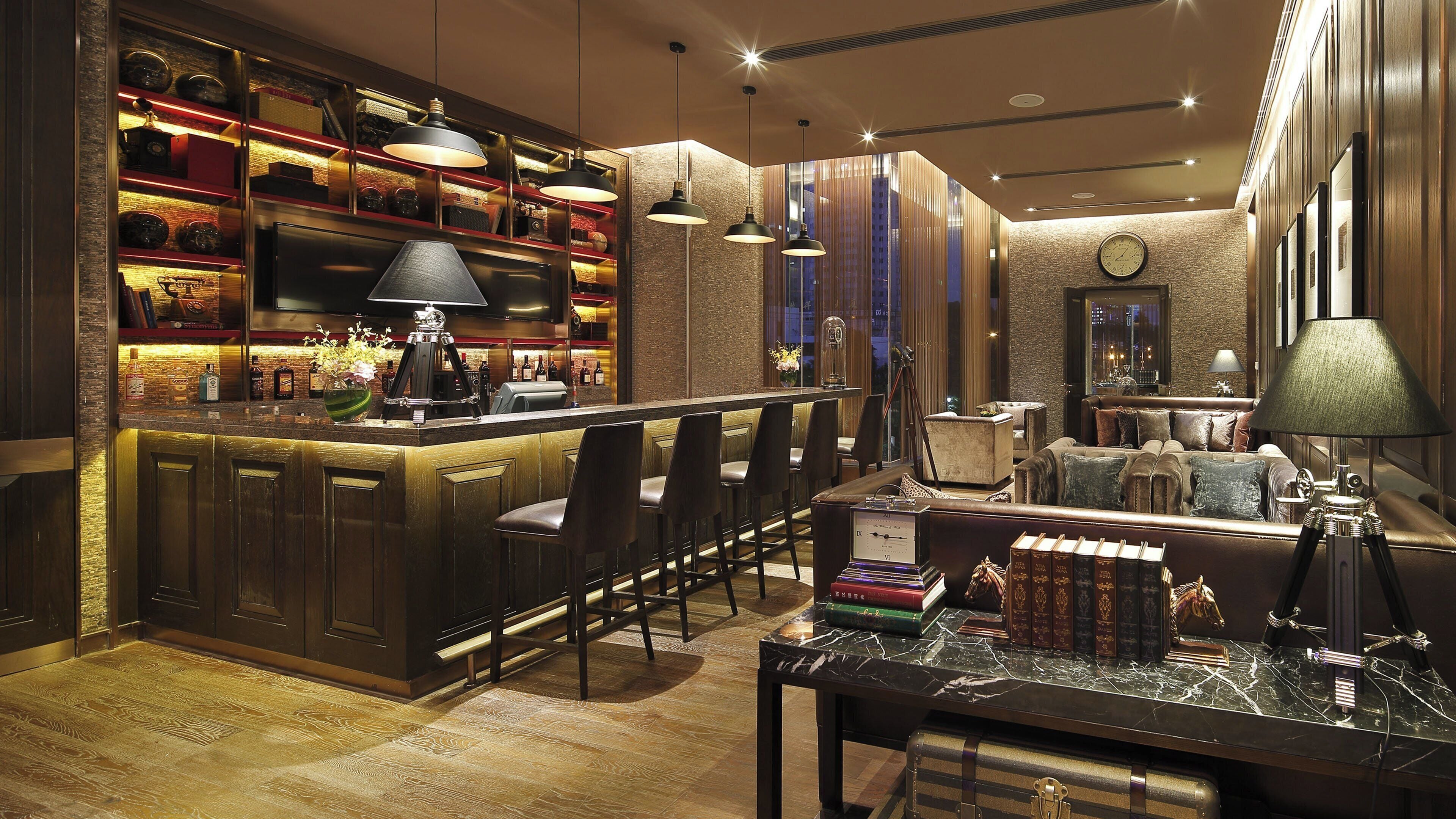 A bar area with a counter, bar stools, and a seating area with a sofa and armchairs.