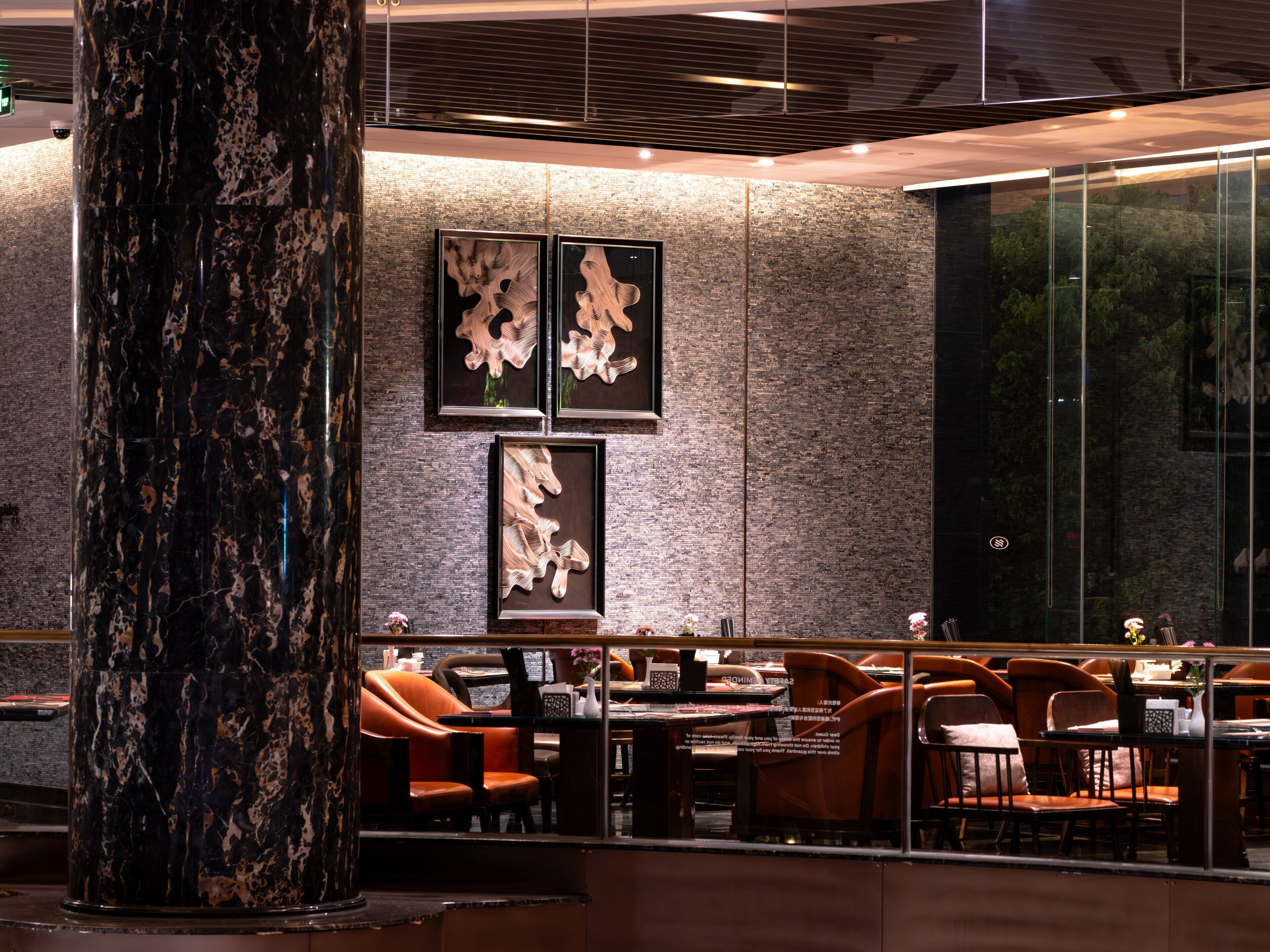 Un intérieur de restaurant moderne, avec des colonnes en marbre, des sièges en cuir et des œuvres d’art abstraites accrochées aux murs.