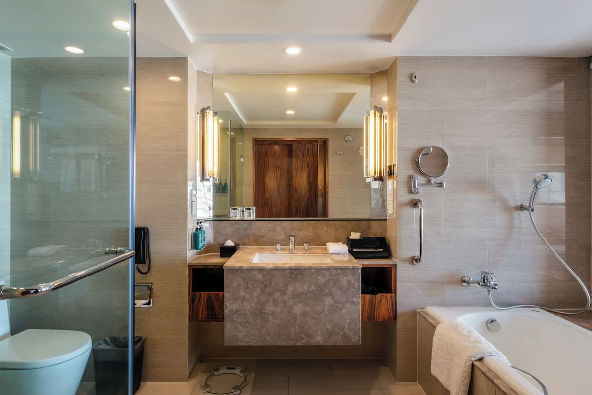 Un baño moderno con cabina de ducha de vidrio, ducha a ras de suelo, bañera y tocador con espejo.