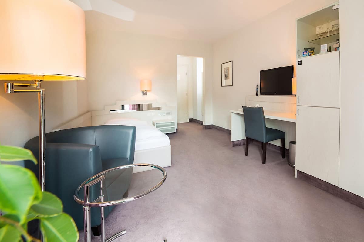 Ein Hotelzimmer mit einem Bett, einem Schreibtisch, einem Stuhl, einem Fernseher und einer Lampe.