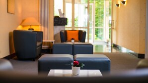 Eine moderne Hotelhalle mit Sitzgelegenheit, darunter zwei Sofas und ein kleiner Tisch mit Blumen.'
