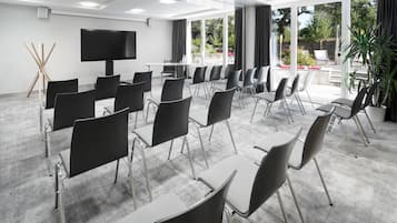 A conference room with a large flat-screen TV, rows of chairs, and a carpeted floor.