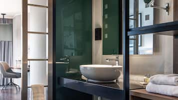 Une salle de bain moderne avec un grand miroir, un lavabo blanc et une serviette posée sur le comptoir.