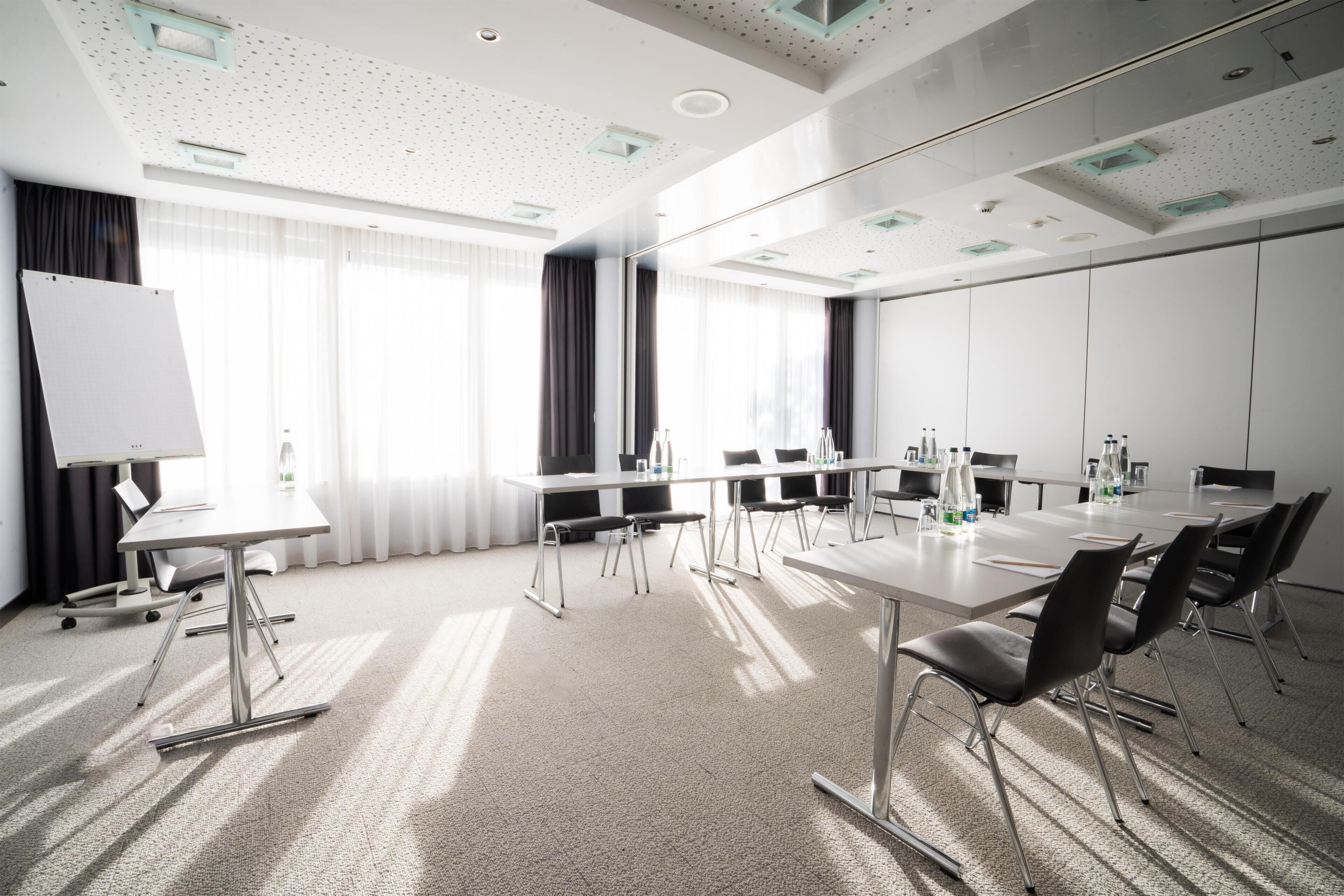 A conference room with a whiteboard, tables, chairs, and a large window with curtains.