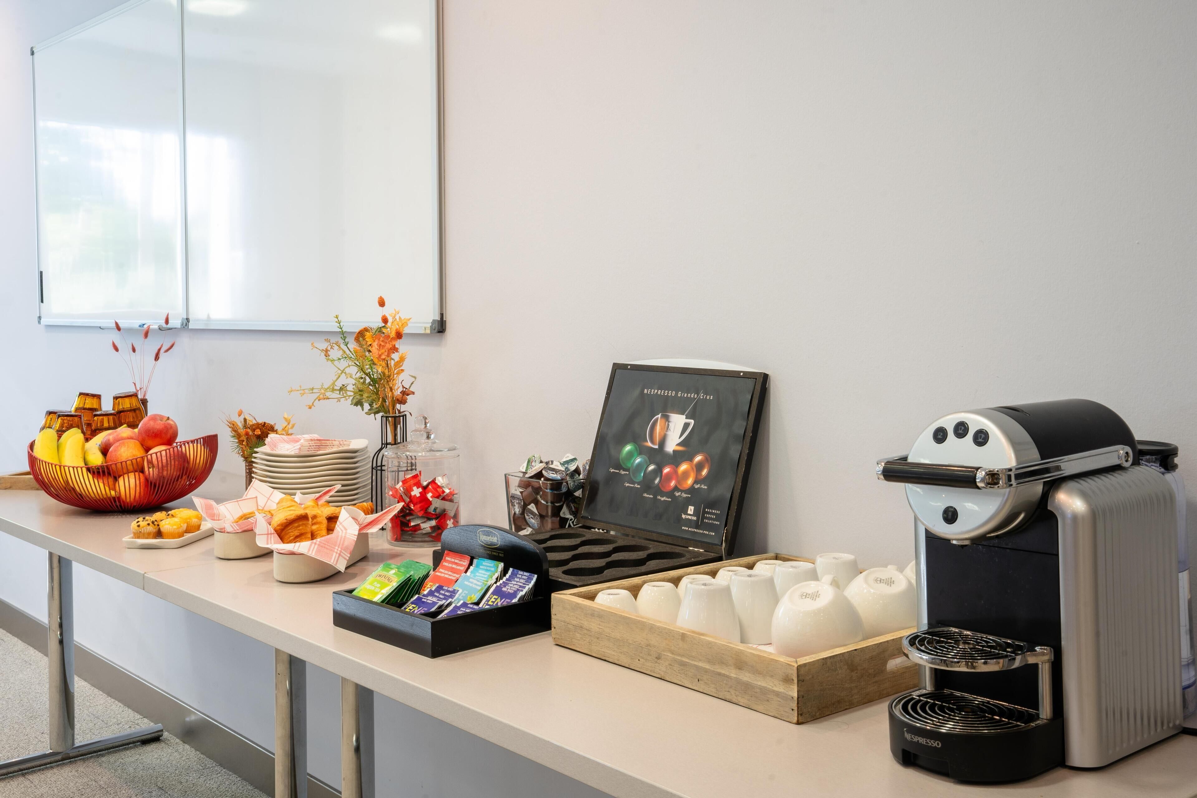 Una barra de desayuno con una máquina de café, un frutero, pastelería y un menú de café.