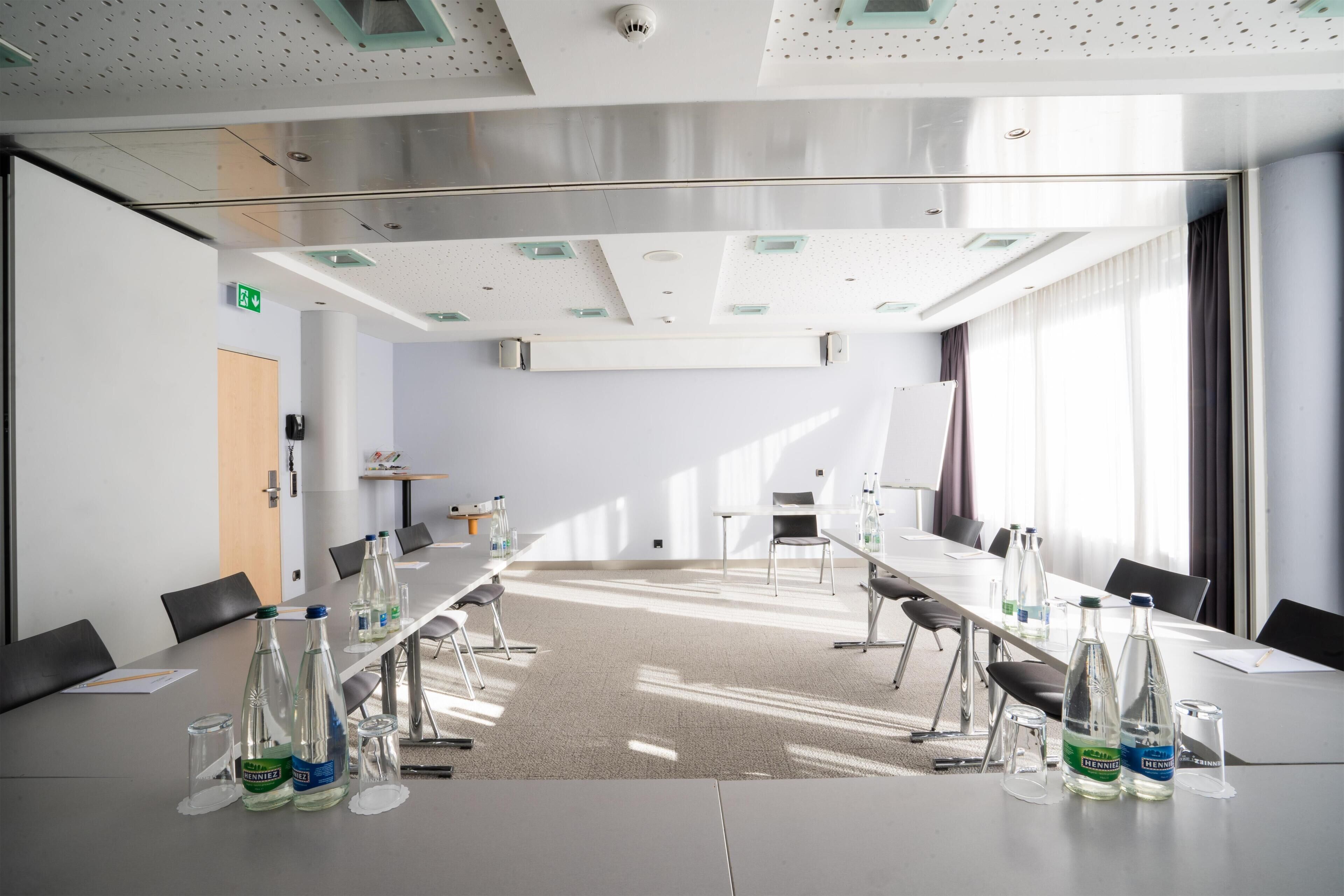 A conference room with a long table, chairs, and water bottles.