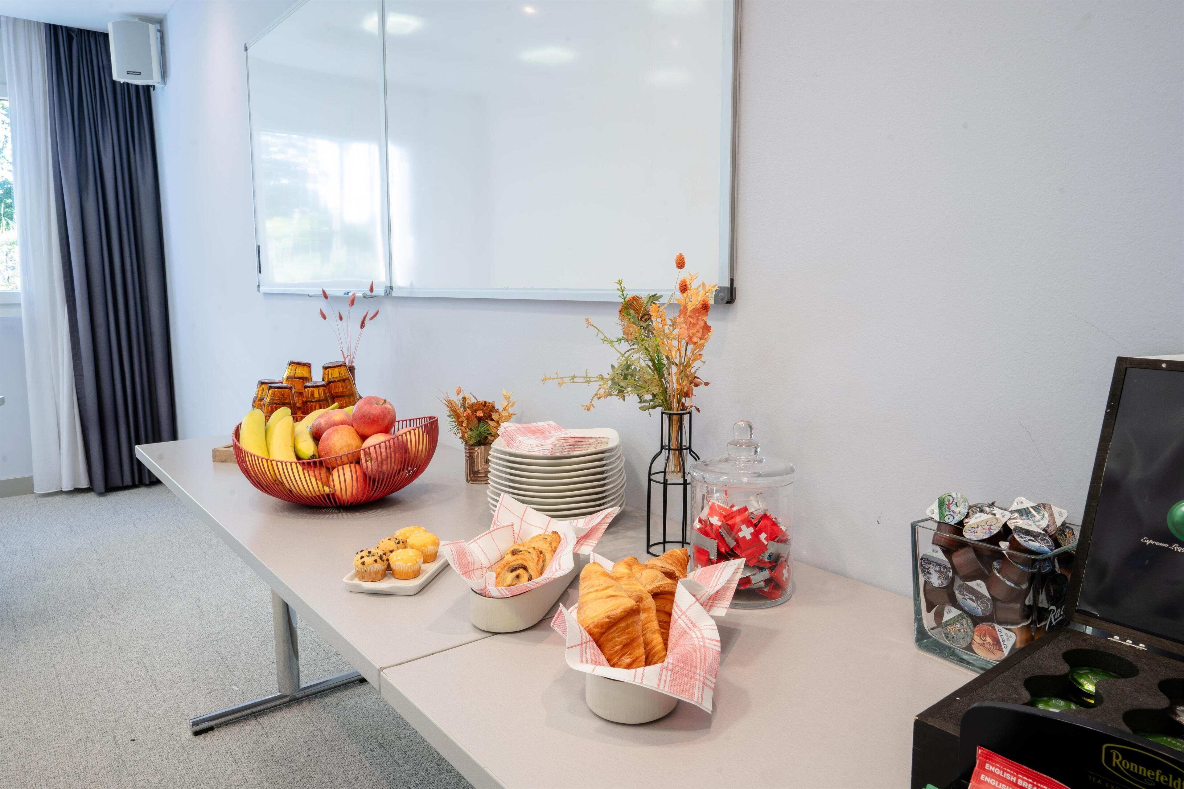 A buffet table with fruits, pastries, and a coffee station.