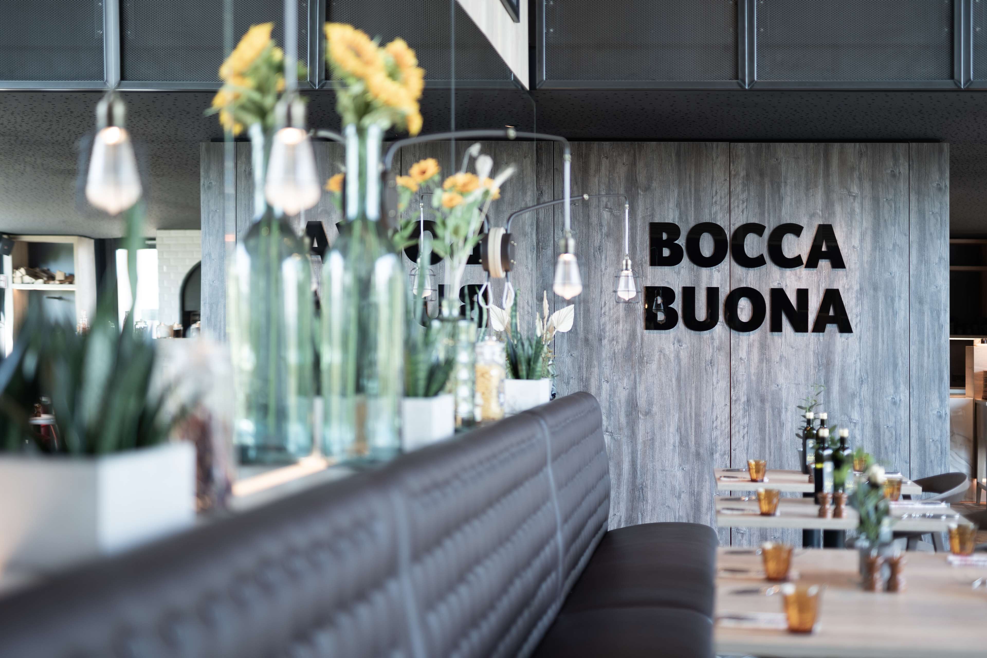 A modern interior with a wooden wall and the text "BOCCA BUONA" in bold letters.