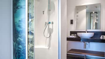 Un baño moderno con ducha acristalada, lavamanos y espejo.