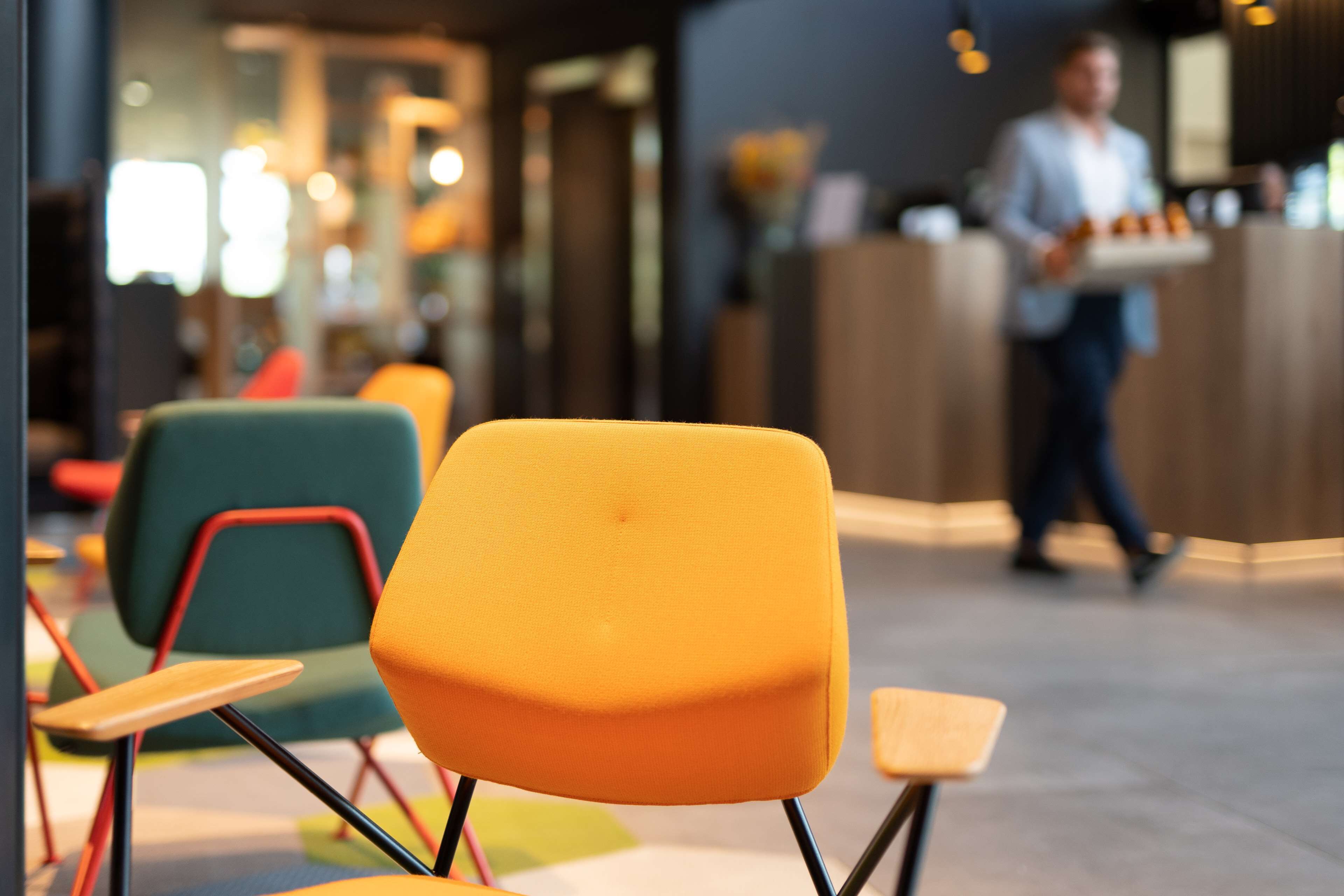 A modern interior with colorful chairs and a person walking in the background.