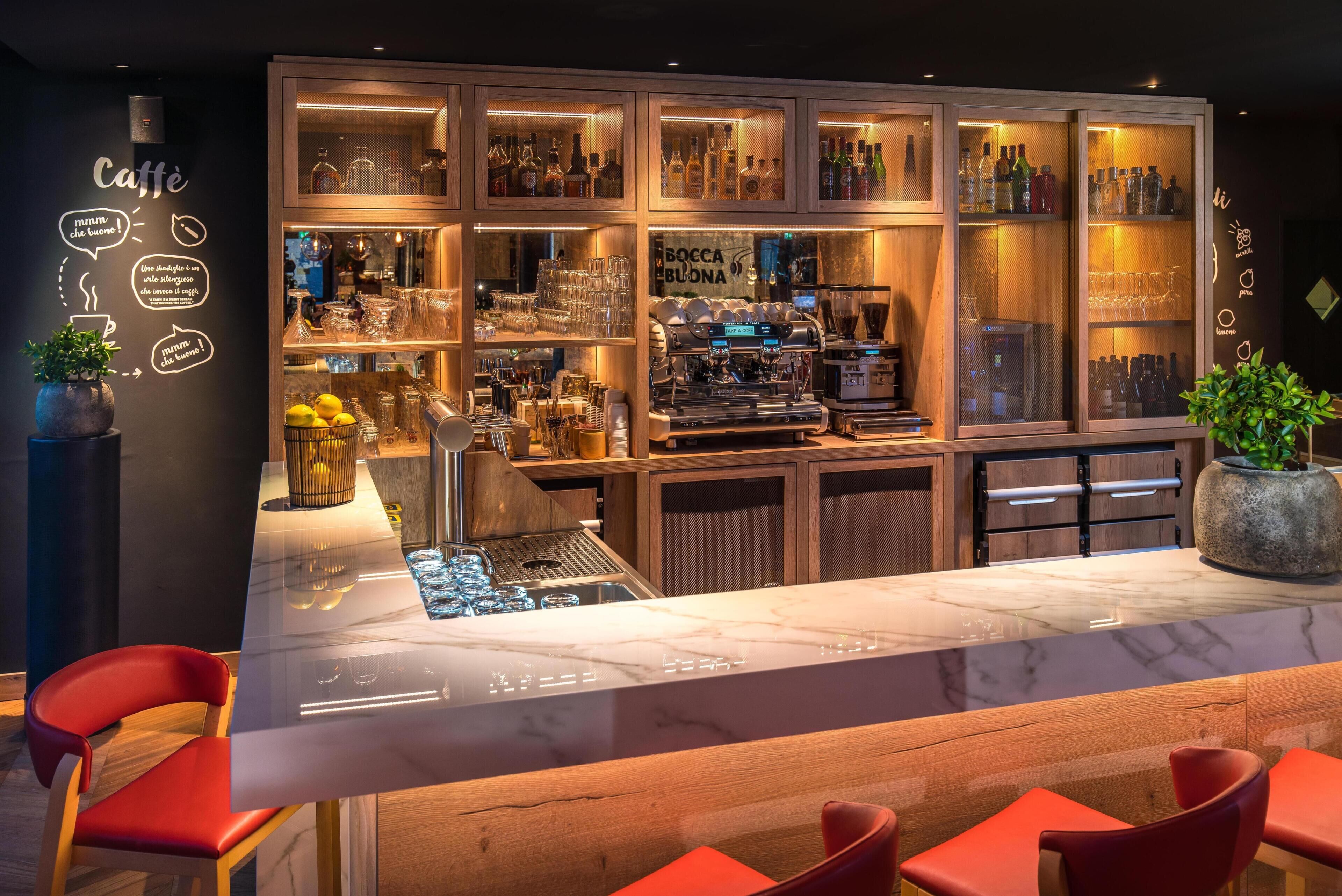 A bar area with a marble countertop, red chairs, and shelves of liquor bottles.
