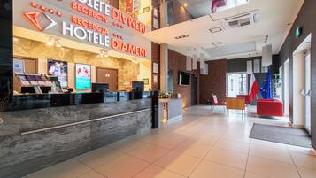 A hotel reception area with a marble counter, a digital screen, and a flag.