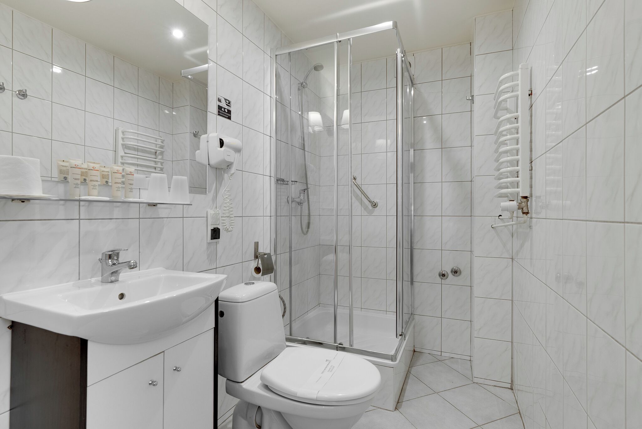 Un baño moderno con lavamanos, inodoro y ducha con mampara de vidrio.