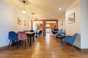 A spacious dining area with wooden flooring, modern chairs, and pendant lighting.