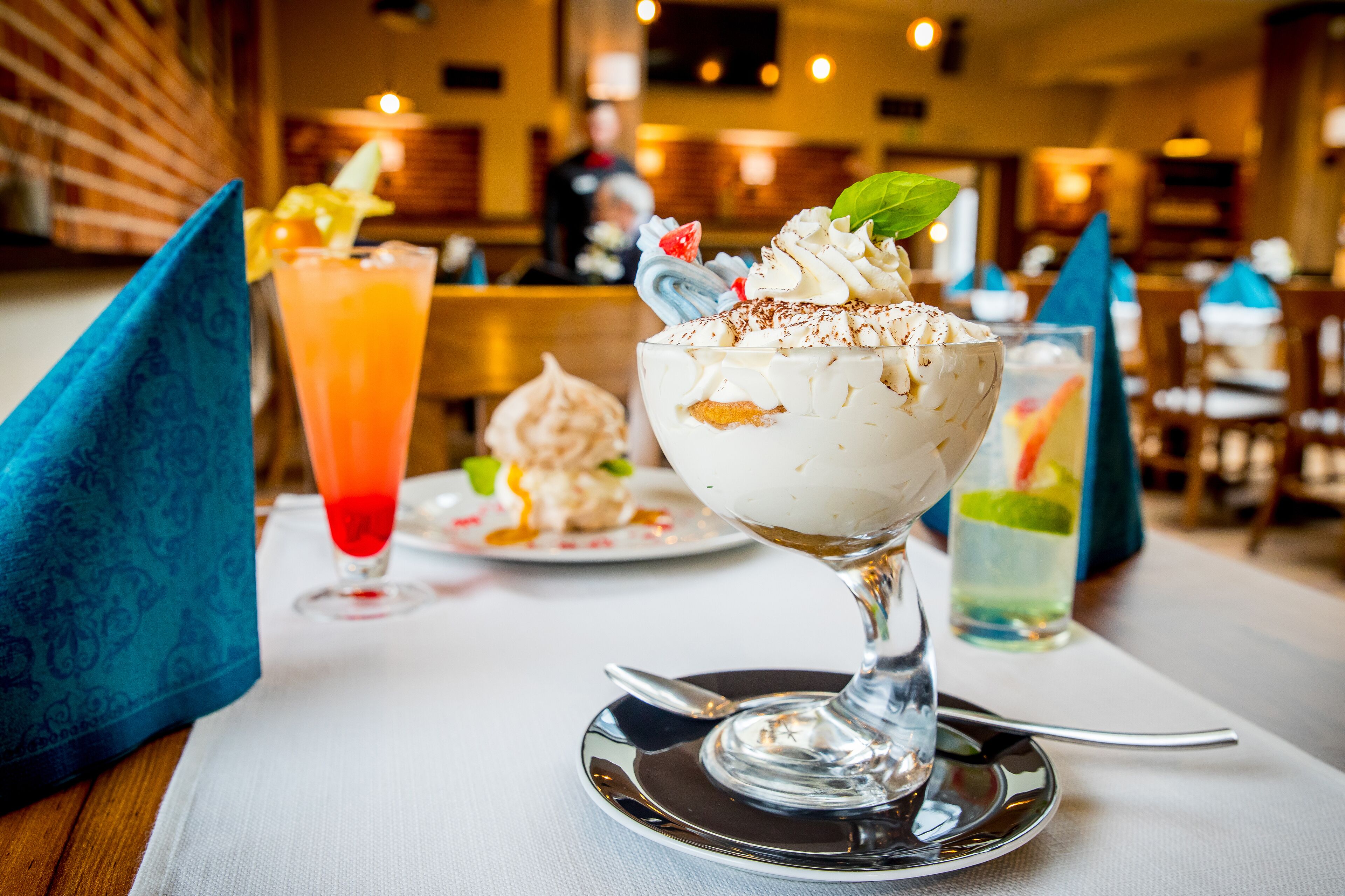 A dessert with whipped cream and a mint leaf on a glass plate.