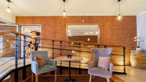 A modern interior with brick walls, a wooden staircase, and two armchairs. - Hotel Diament Zabrze (Zabrze)