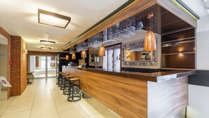 A modern bar area with a wooden counter, hanging pendant lights, and a seating area with chairs. - Hotel Diament Zabrze (Zabrze)