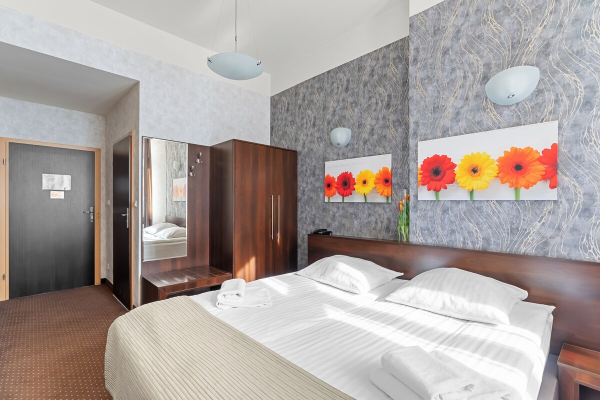 Une chambre d’hôtel avec un grand lit, une armoire en bois et un miroir.