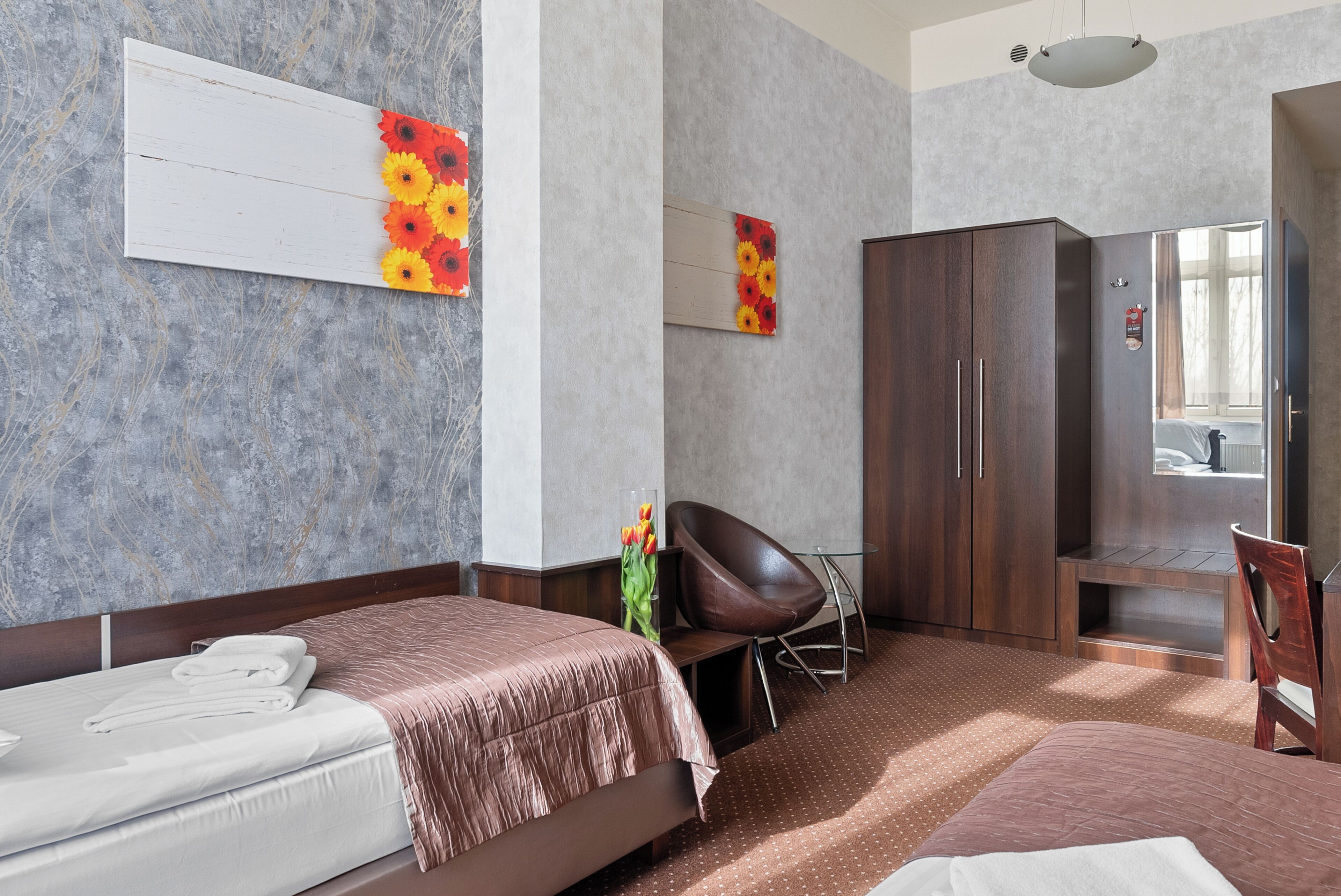 Une chambre d’hôtel avec un lit, une chaise, une armoire et un miroir.