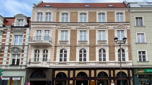 Un edificio de varios pisos con fachada clásica, que presenta ventanas en arco y molduras decorativas.