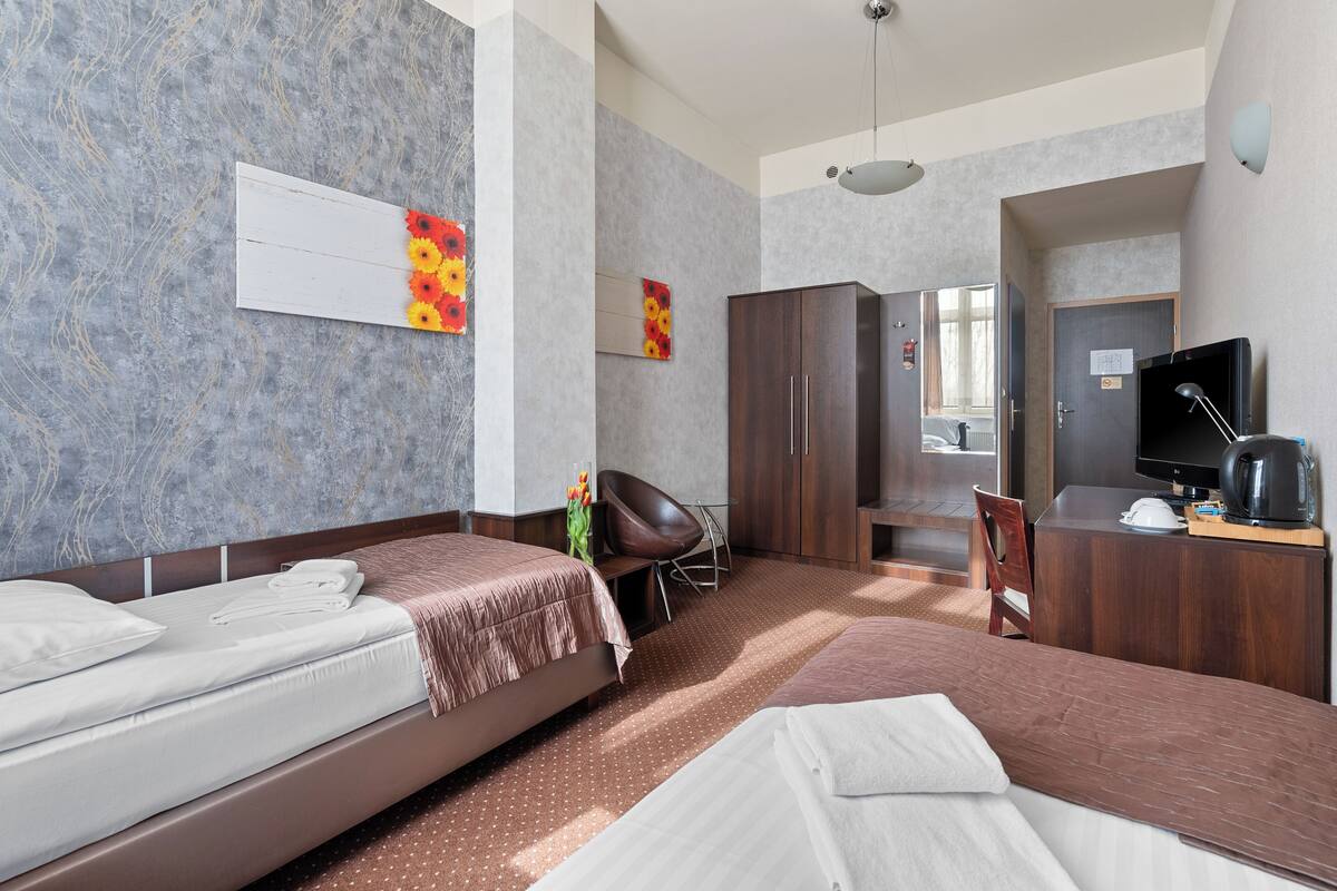 Een hotelkamer met twee bedden, een bureau, een stoel, een televisie en een kledingkast.