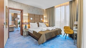 Habitación de hotel con una cama grande, mesitas de noche, un escritorio, una silla y vistas a la ciudad.