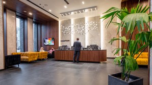 Una zona de recepción moderna con un mostrador de madera, una amplia pantalla digital y asientos cómodos.