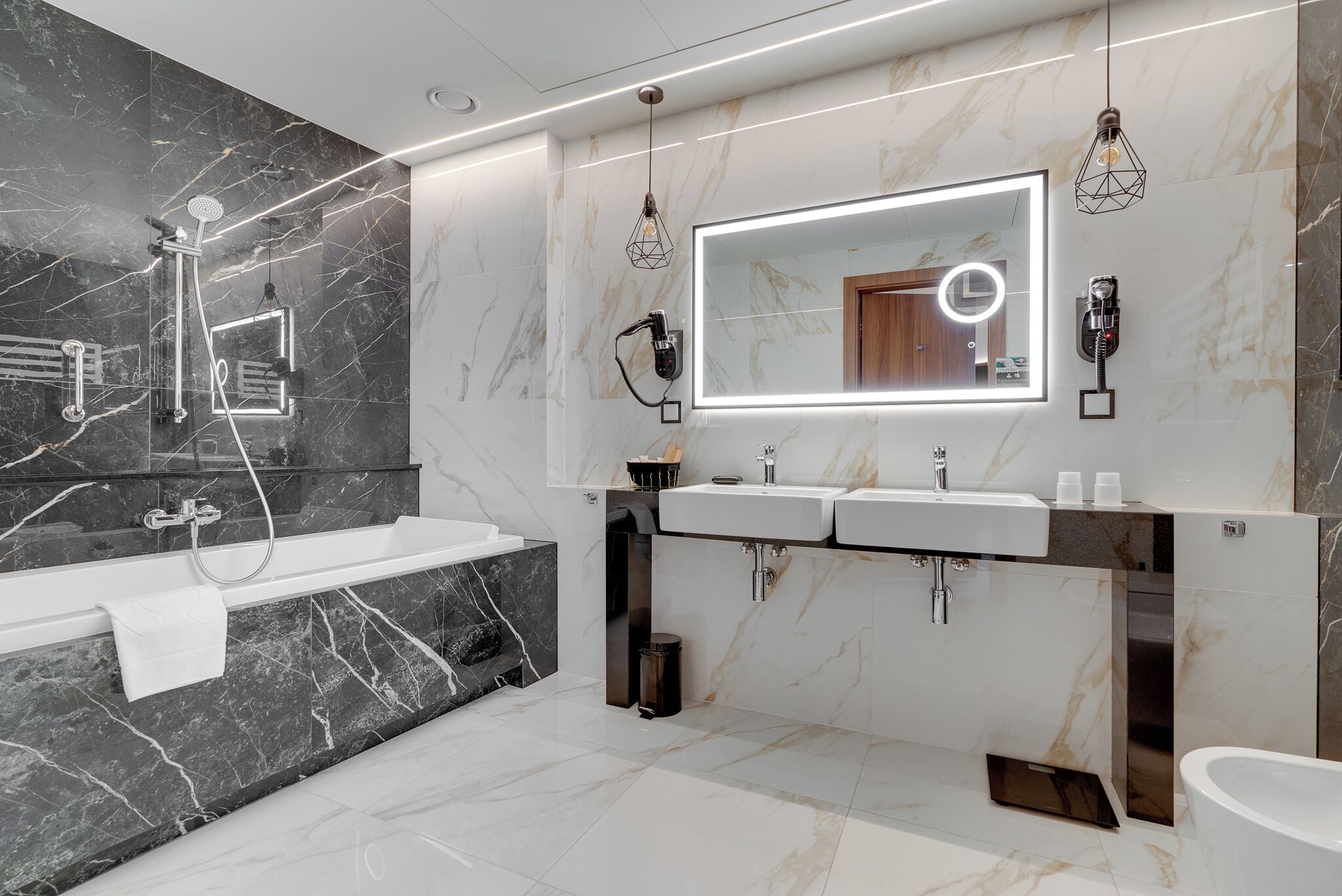 Un baño moderno con un espejo grande, dos lavamanos, una bañera y una ducha.