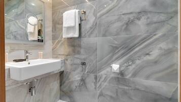 Ein Badezimmer mit Marmorwand, Waschbecken, Spiegel und Handtuchhalter.