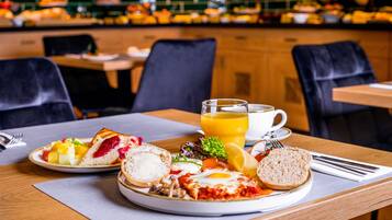 A breakfast setting with a plate of toast, eggs, and fruit, a glass of orange juice, and a cup of coffee on a table.