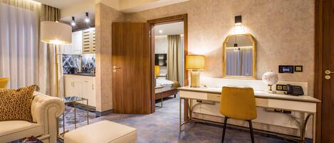 Habitación de hotel con sofá, reposapiés, escritorio, silla y una cama al fondo.