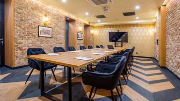 Un salón de conferencias con una larga mesa, sillas negras y una pantalla grande.