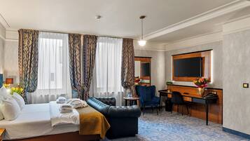 A hotel room with a bed, a desk, a chair, a television, and a large window with curtains.