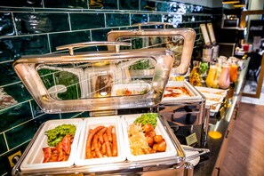 Un bufé con diversas opciones de comida, como brócoli, salchichas y fideos.