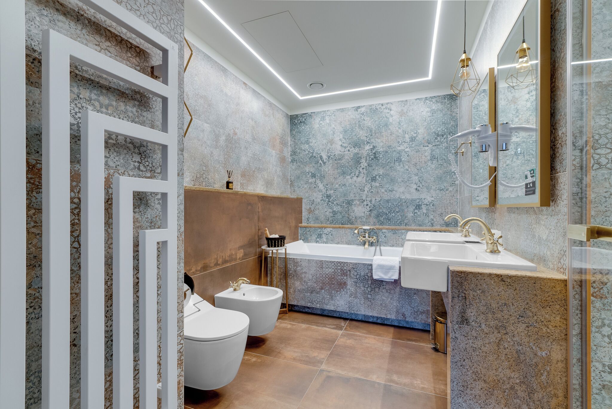 Un bagno moderno con una vasca da bagno freestanding, due servizi igienici e un mobile lavabo con uno specchio grande.