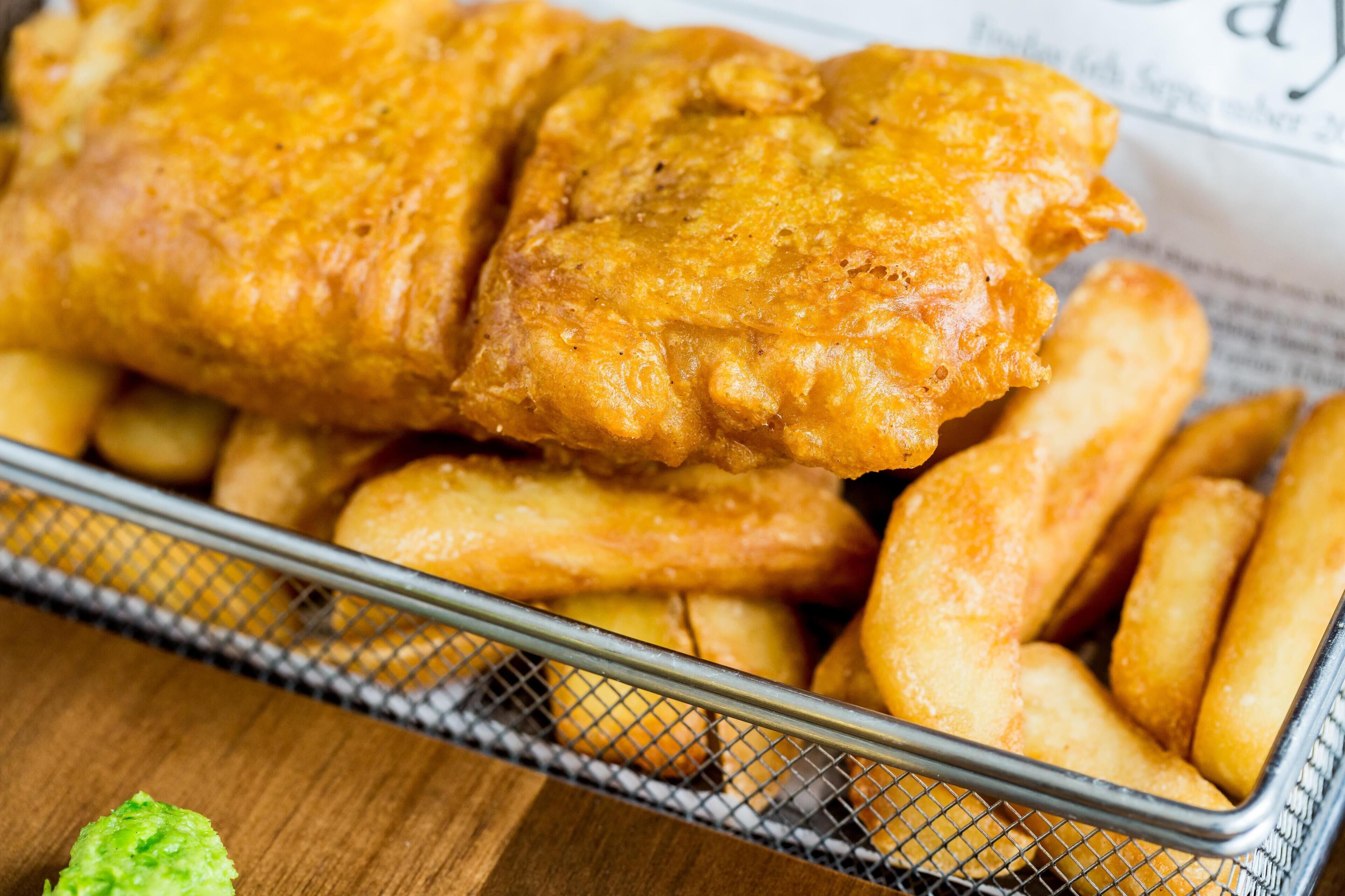A basket of fried fish and chips with a green garnish.