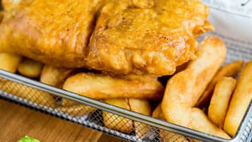 A basket of fried fish and chips with a green garnish.