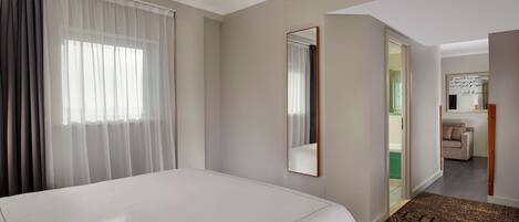 Habitación de hotel con una cama grande, un espejo y vistas al baño y la sala de estar.