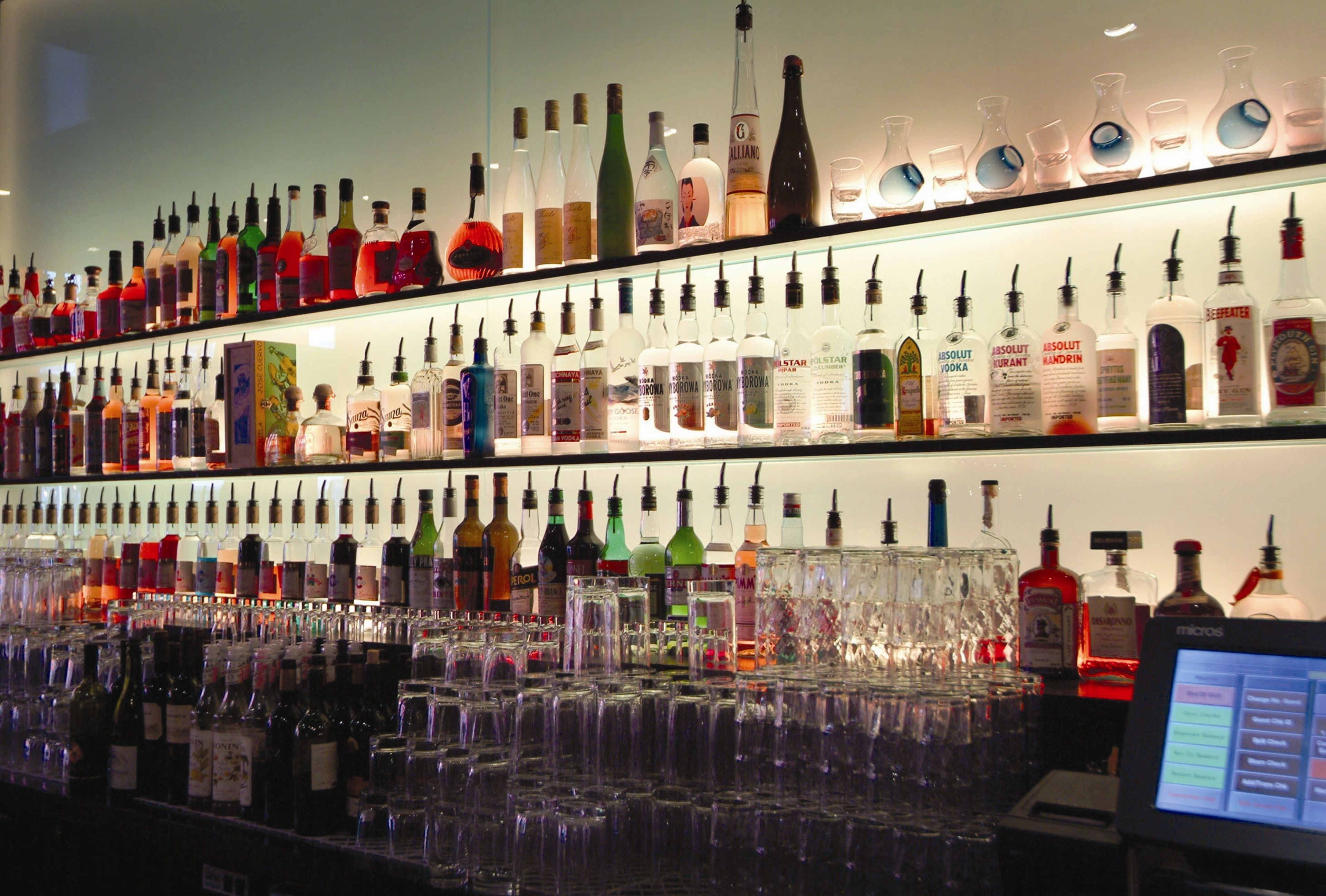 A bar with multiple shelves of liquor bottles and glasses.