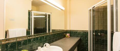 Baño con lavamanos, espejo y ducha.