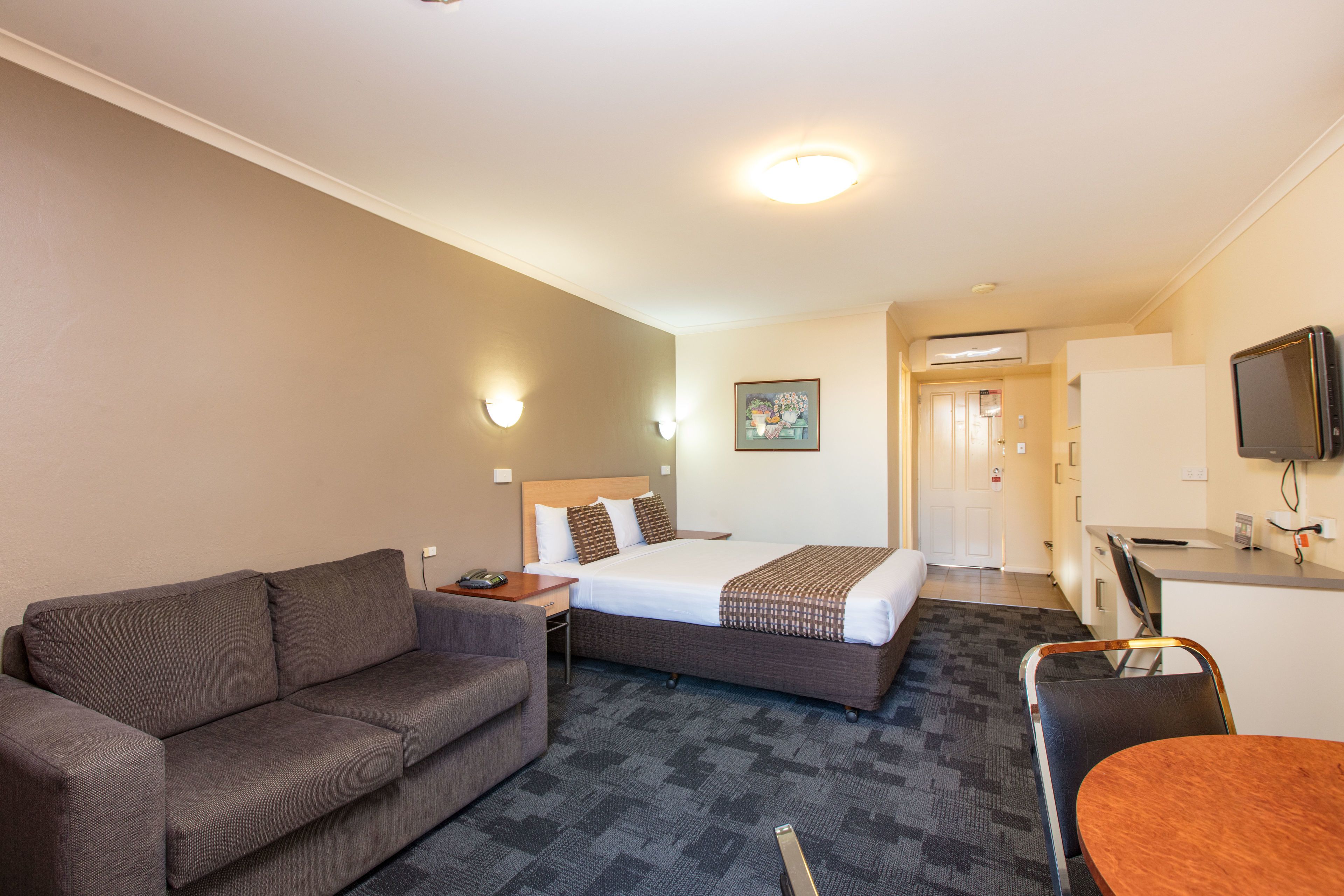 Une chambre d’hôtel avec un lit, un canapé, un bureau et une télévision.