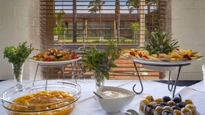 Una mesa de buffet con diversos alimentos, como frutas, pasteles y un tazón de sopa.