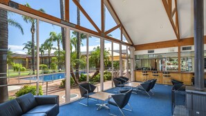 Un amplio espacio interior con ventanas grandes, vista a la piscina y zona de bar.