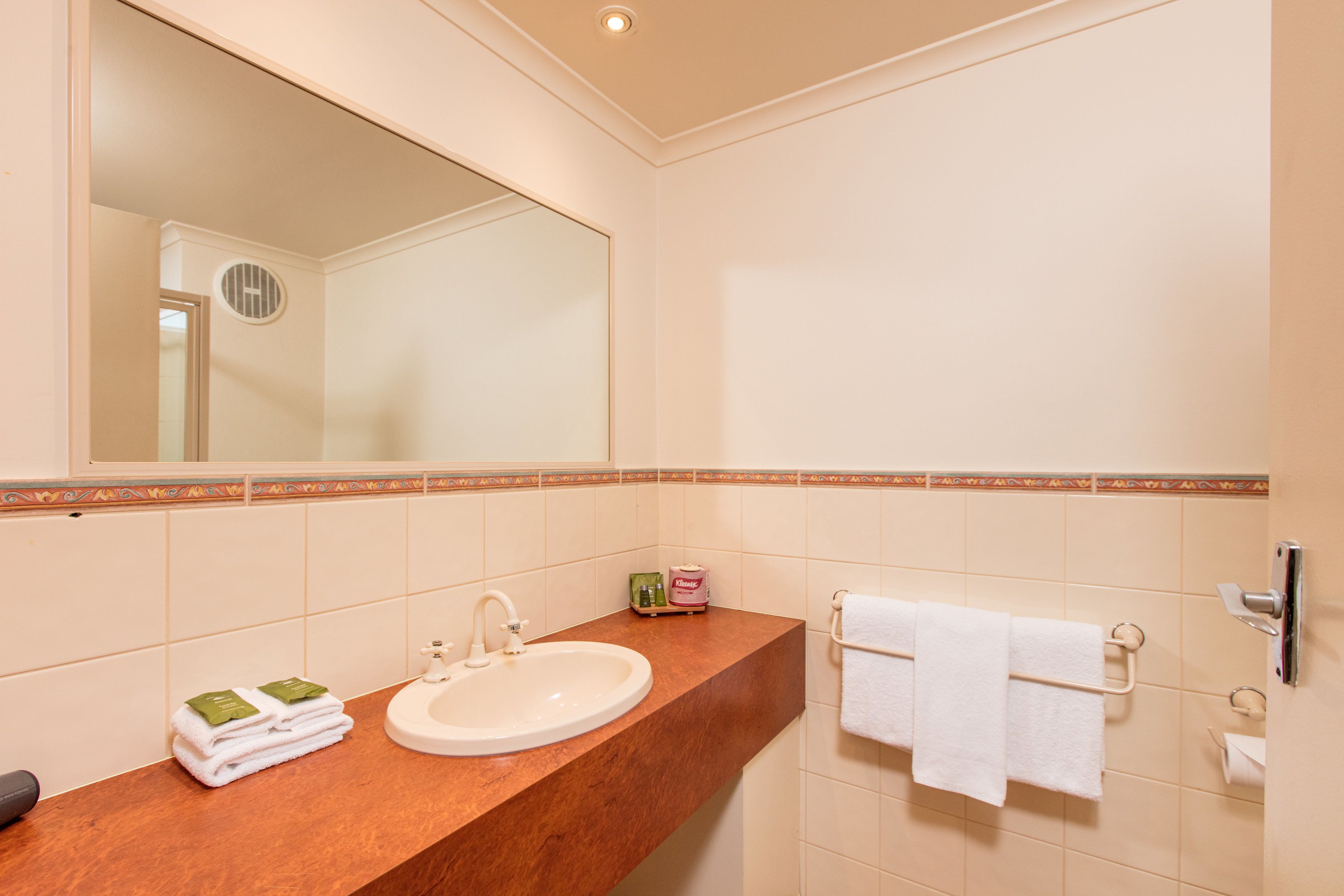 A bathroom with a sink, mirror, towel rack, and toiletries.