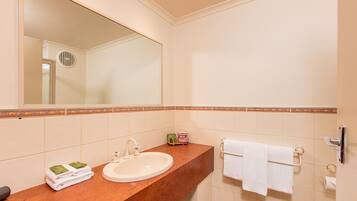 A bathroom with a sink, mirror, towel rack, and toiletries.