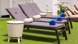 A set of lounge chairs with cushions, a small table with a vase of flowers, and a potted plant. - Hotel LIVVO Fataga (Las Palmas de Gran Canaria)