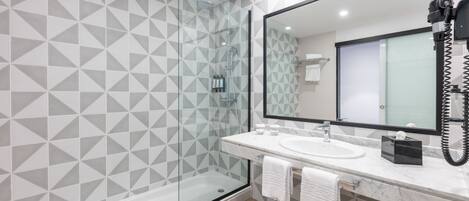 Une salle de bain moderne avec une douche à parois de verre, un grand miroir et un lavabo en marbre.