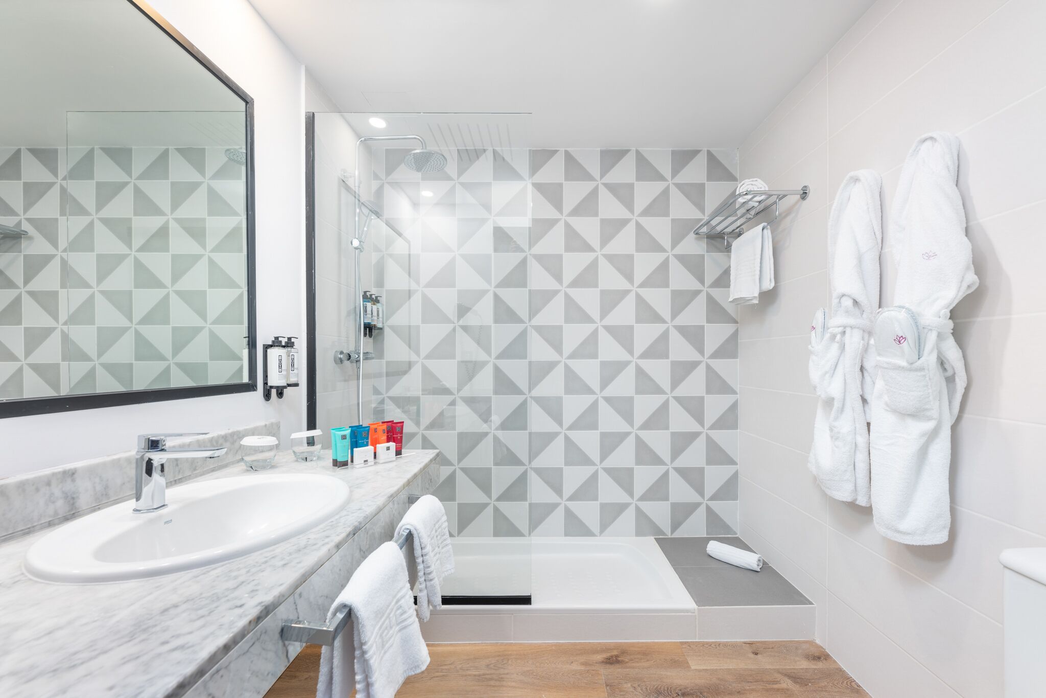 A modern bathroom with two sinks, a large mirror, a shower, and a bathtub.