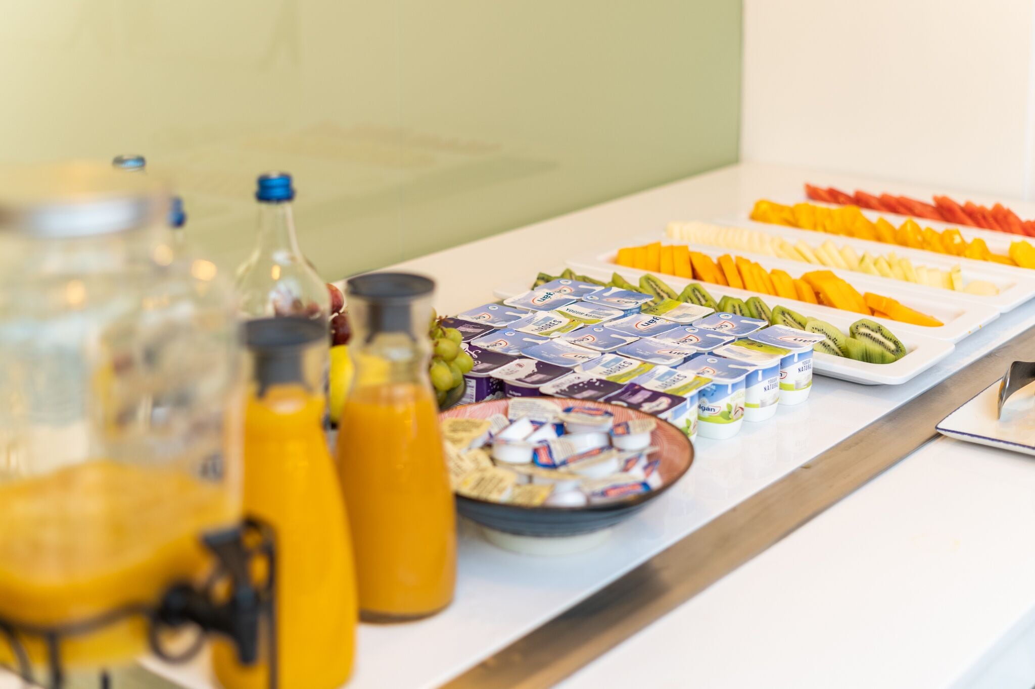 A breakfast buffet with various fruits, yogurt, and juice.