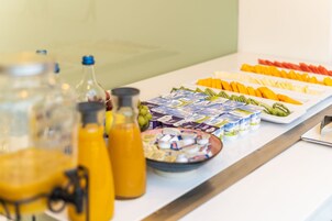 Un buffet della colazione con frutta, yogurt e succhi di frutta assortiti.